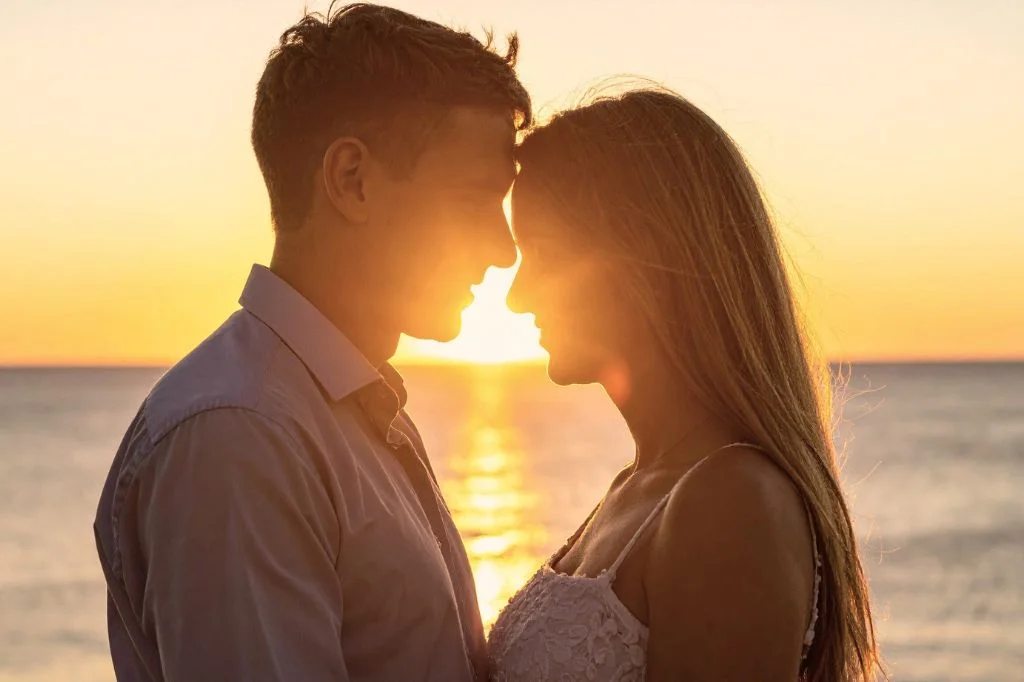 A couple enjoying a safe and romantic holiday romance on a Bali beach at sunset.