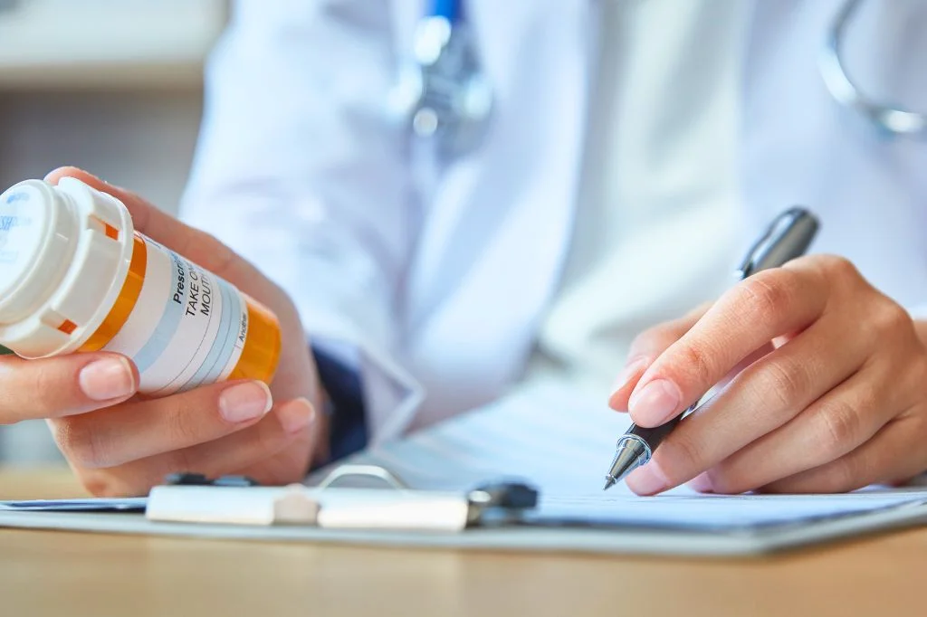 A doctor handing a prescription or medication to a patient while explaining the treatment instructions.