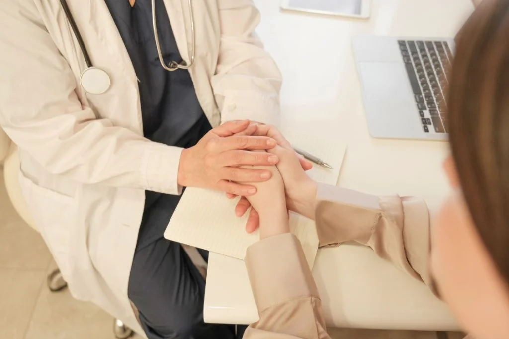 A doctor at a Bali clinic holds patient's hands, giving comfort.