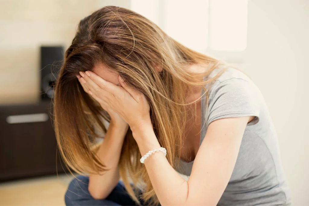 A person in Bali holding her head, feeling worried after unsafe sex.