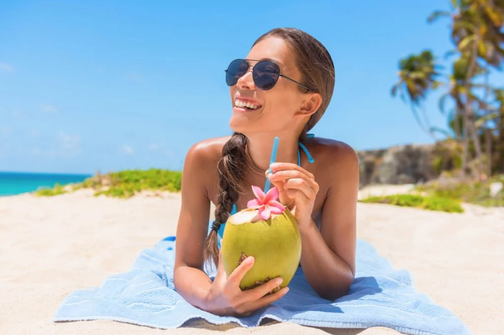 Tourist enjoying a fresh coconut in Bali, staying hydrated to prevent health issues.