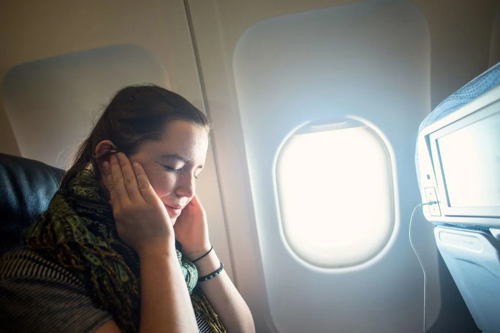 A traveler experiencing ear pain and pressure (airplane ear) after landing in Bali.