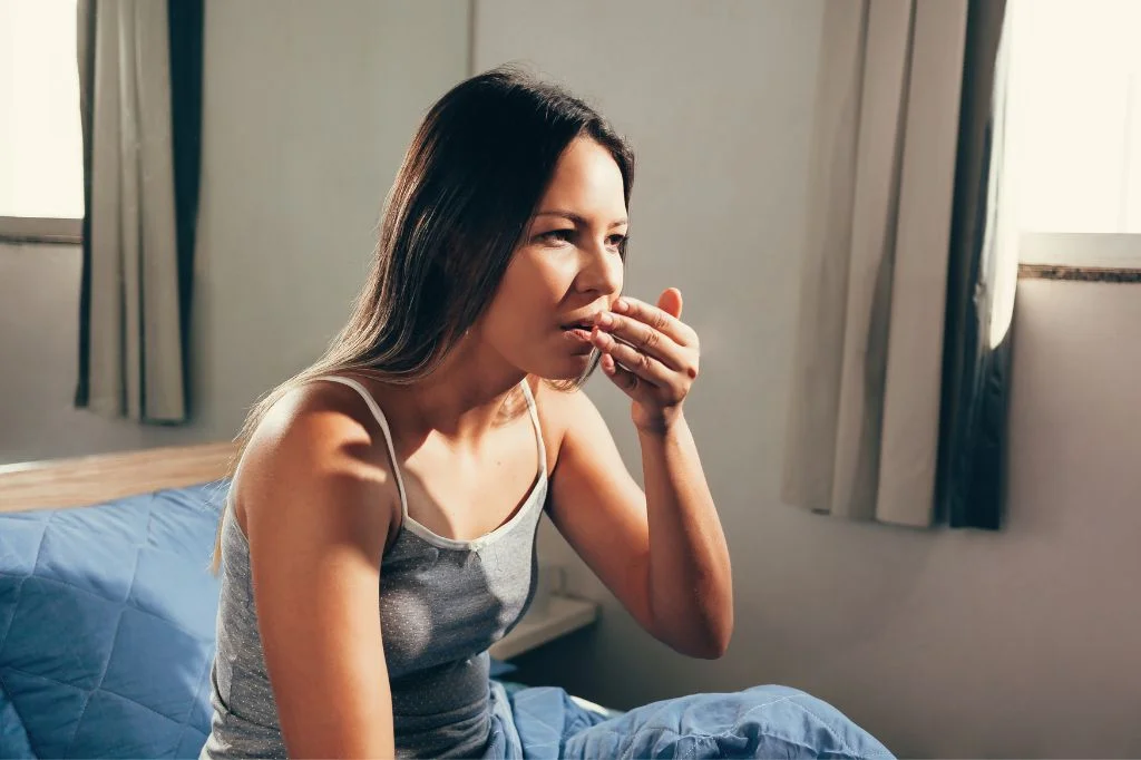 A tourist checking for bad breath, a common symptom of tonsil stones (tonsilloliths).