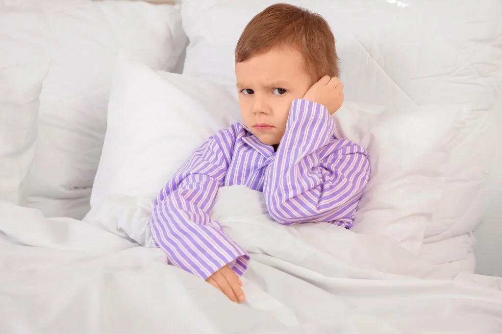 A toddler pulling their ear and crying, often mistaken for teething but could be an ear infection.