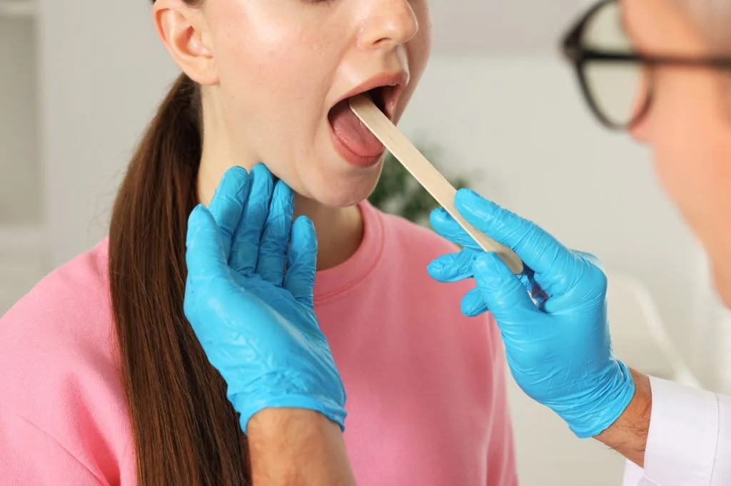 Hydro Medical doctor examining a patient's tonsils for white patches or inflammation.