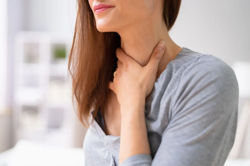 A tourist in Bali holding their throat due to sudden loss of voice (laryngitis).