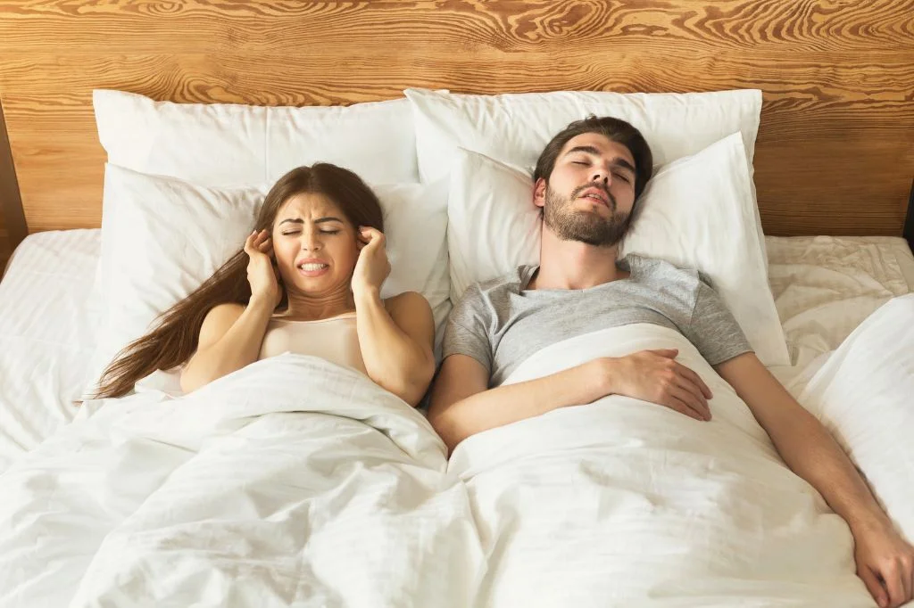 A partner covering their ears due to sudden loud snoring during their Bali holiday.