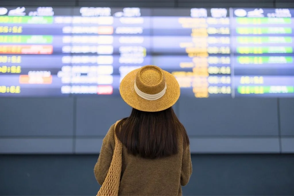 A traveler at the airport holding a Fit to Fly medical certificate and luggage, preparing for a safe flight home.