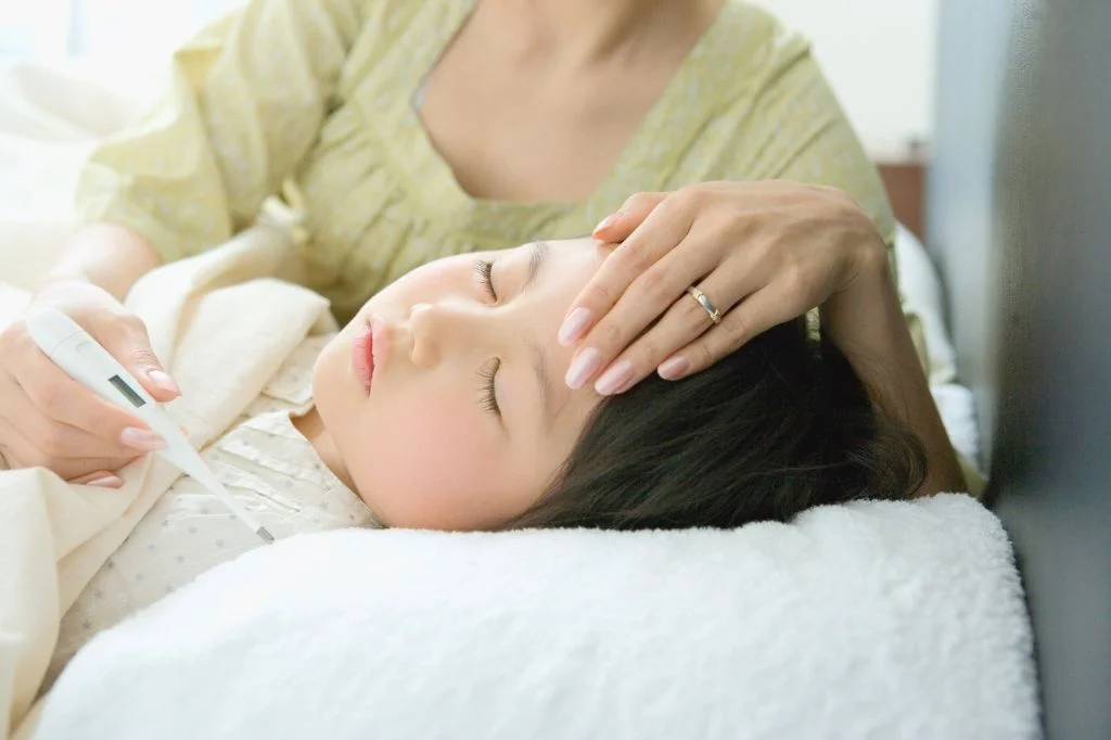 A parent checking a sick child's temperature and treating a sore throat safely while on holiday in Bali.