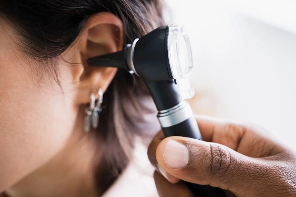 An ENT doctor performing a thorough ear examination using an otoscope to diagnose infection or blockages.