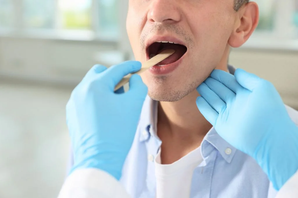 A doctor performing a thorough throat examination to diagnose the cause of sore throat at Hydro Medical Bali.