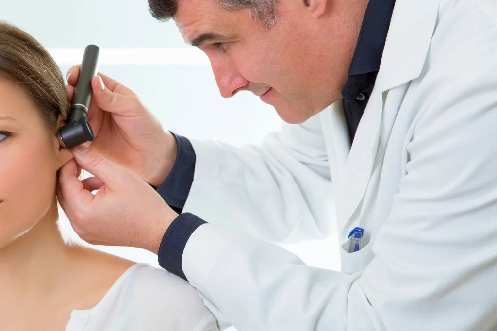An ENT doctor examining a patient's ear to assess the risk of barotrauma before a flight.