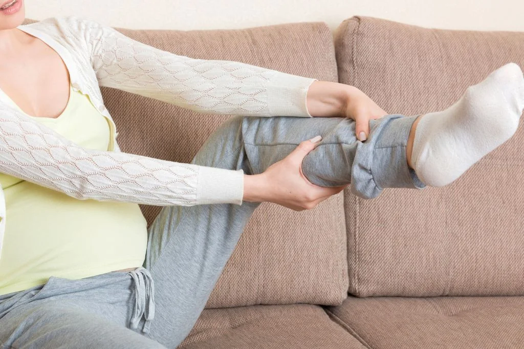 A person lifting up her leg to check the vascular and circulation health at home