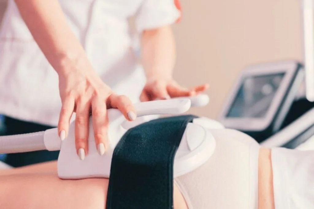 A neatly dressed person is receiving non-surgical muscle-sculpting treatment with CM Slim in a clinic.