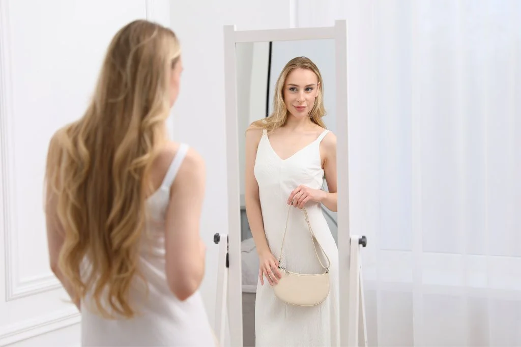 A confident woman in Bali admiring her toned figure while preparing for a special event.