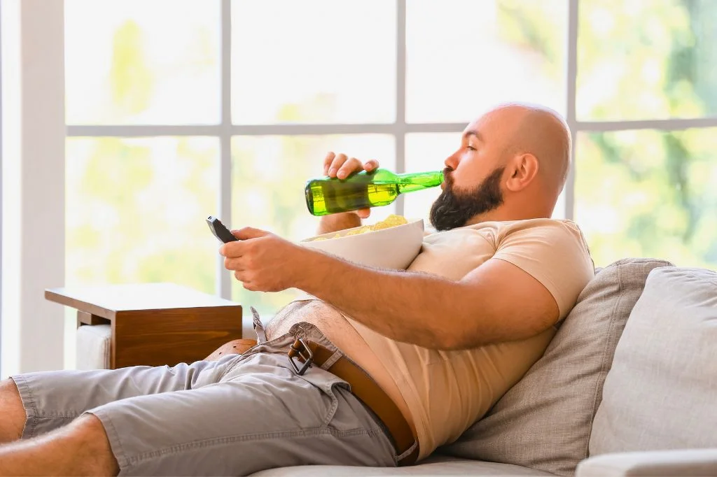 A person in Bali frustrated with stubborn belly fat caused by weekend socializing and a stagnant metabolism.