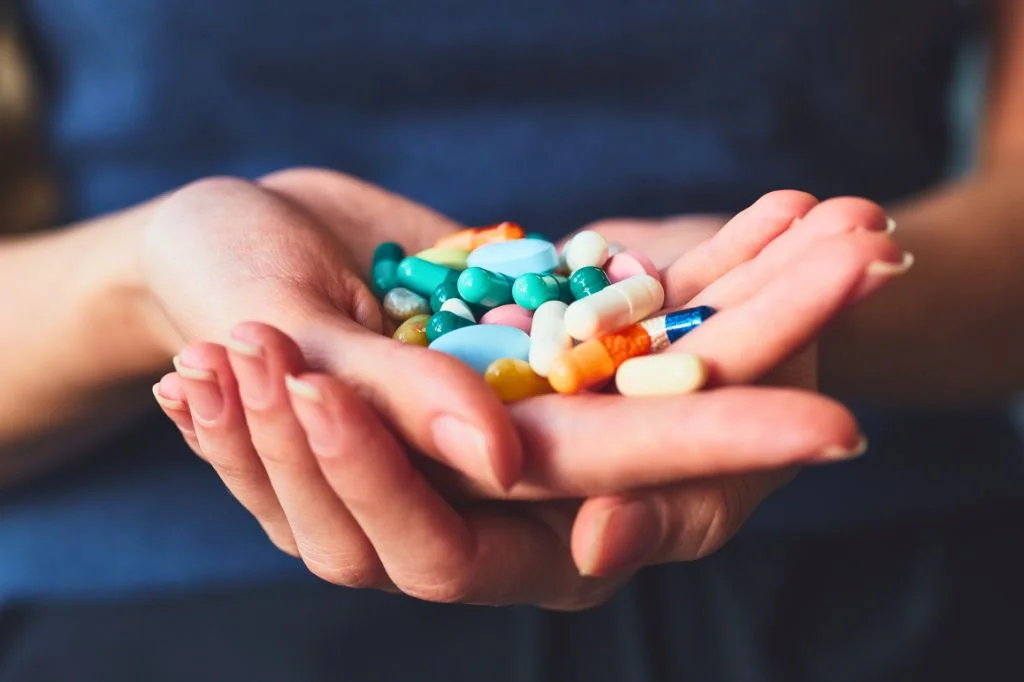 A person holding health supplements, representing a daily vitamin routine.