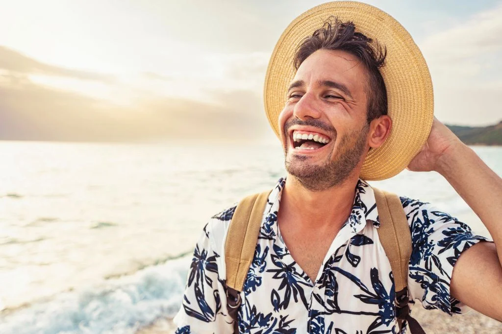 Guy traveler smiling widely, showing healthy gums and teeth in a tropical Bali setting.