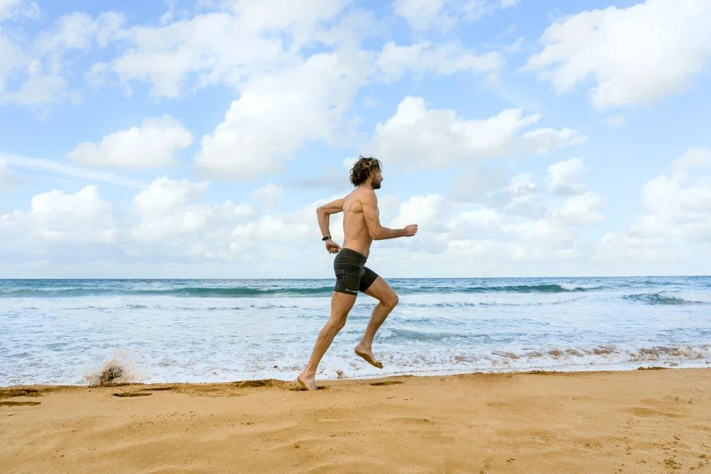 A person running on the sandy beach in Bali, experiencing foot strain.