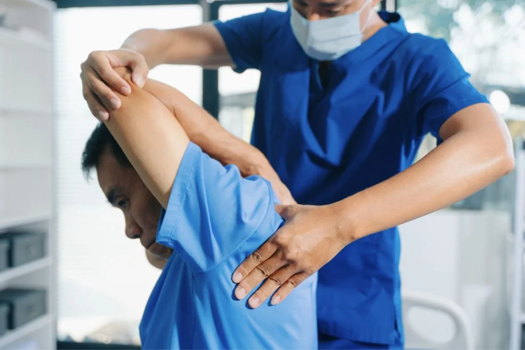 A professional physical therapist at Hydro Medical Clinic Bali providing a shoulder assessment for travel-related strain.