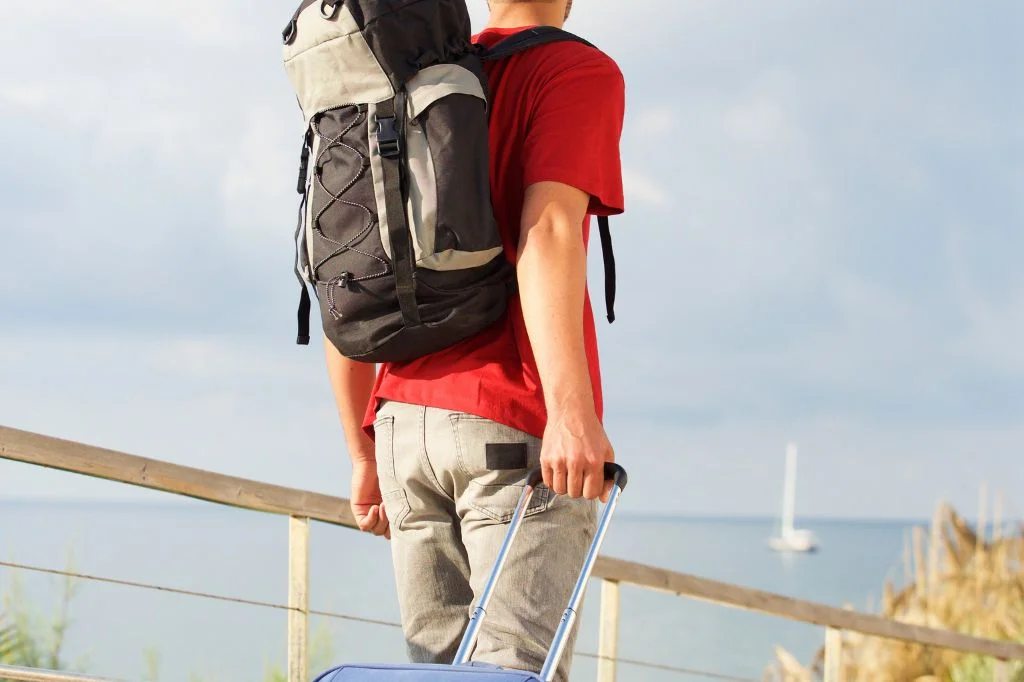 A traveler with a heavy backpack in Bali experiencing shoulder pain or tingling in fingers.