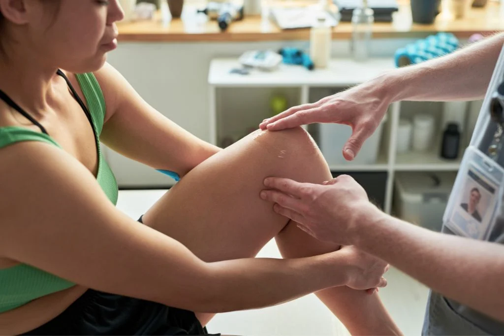 Professional physiotherapist at a Bali clinic examining a patient with a yoga overstretching injury.