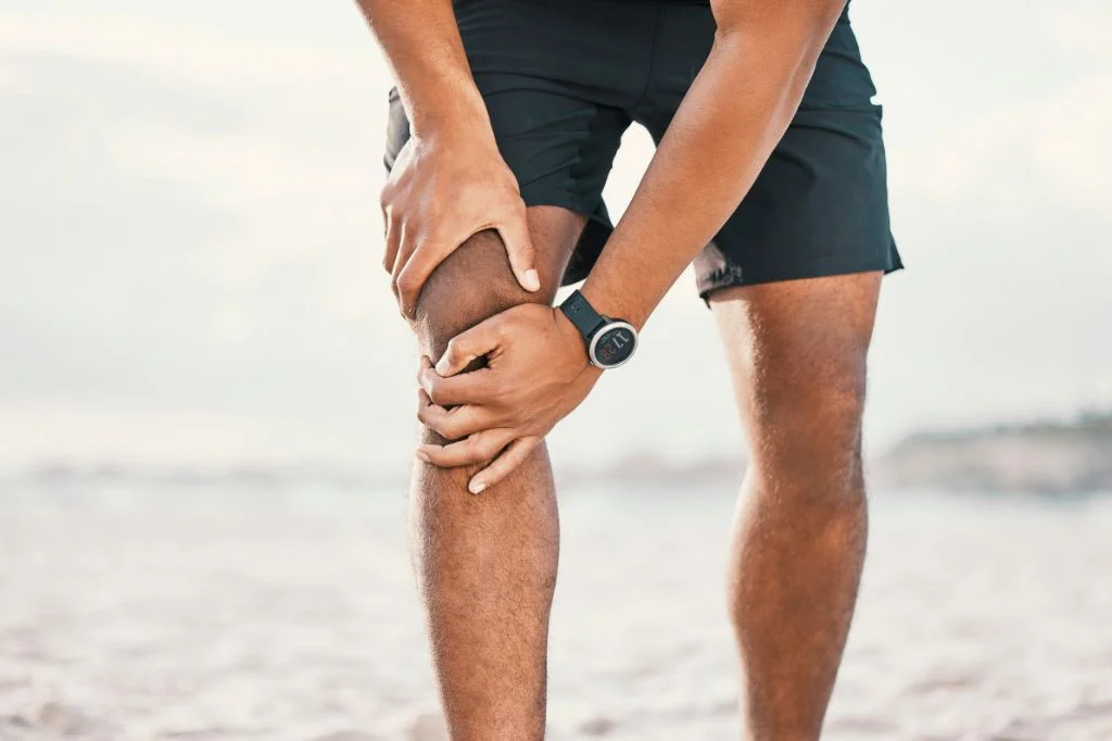 A fitness enthusiast in Bali dealing with sharp lower leg pain from beach running.