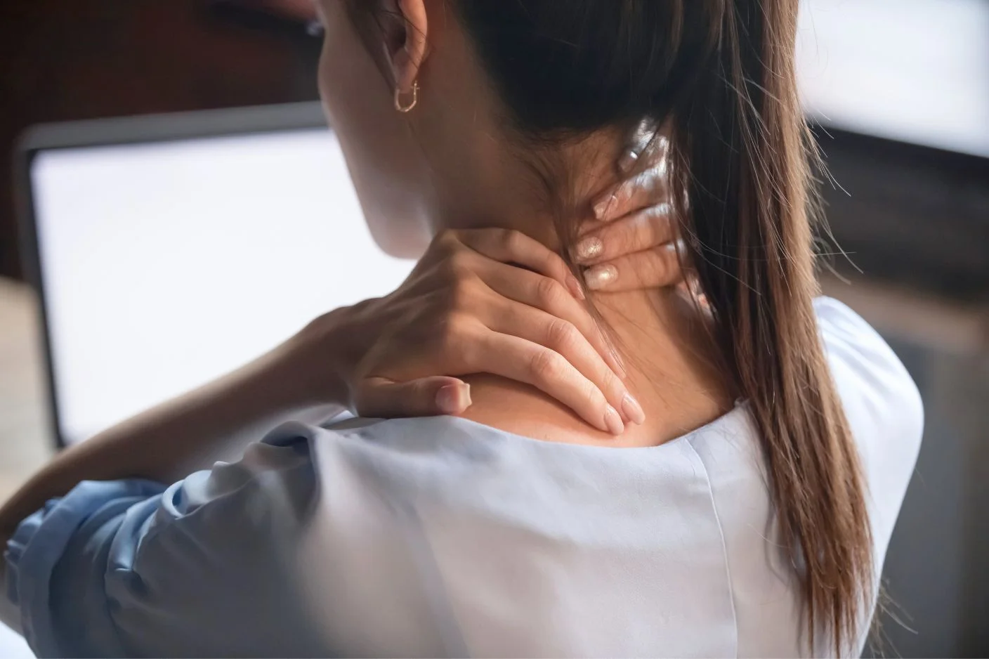 A remote worker in Bali experiencing tech neck symptoms and neck pain from a poor workstation setup.