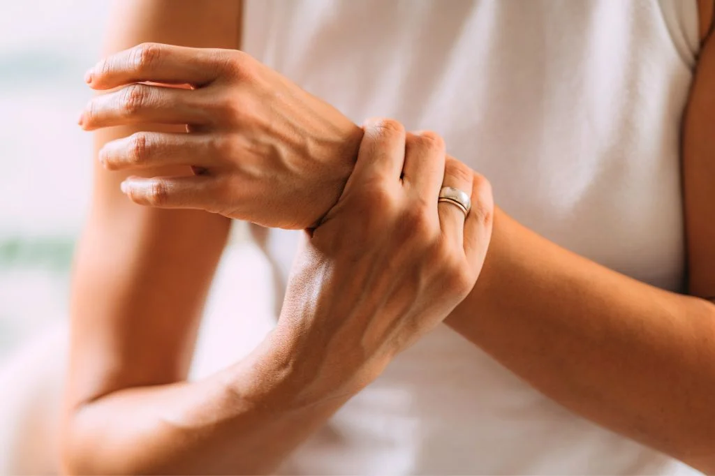 A remote worker in Bali experiencing wrist pain from typing, a common sign of carpal tunnel syndrome.