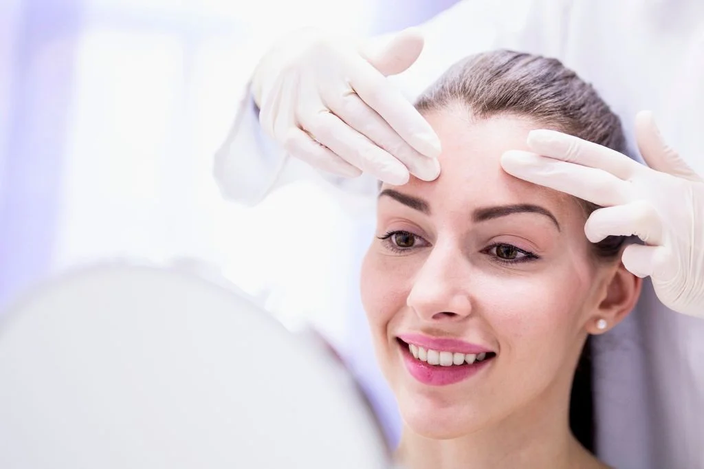 Dermatologist marking treatment points on a patient's forehead before a Botox procedure in a bright Bali clinic