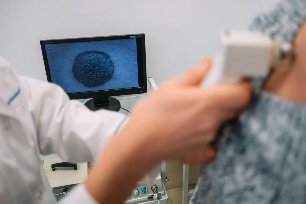 Dermatologist reviewing mole-mapping images on a monitor with a patient in a bright Bali clinic