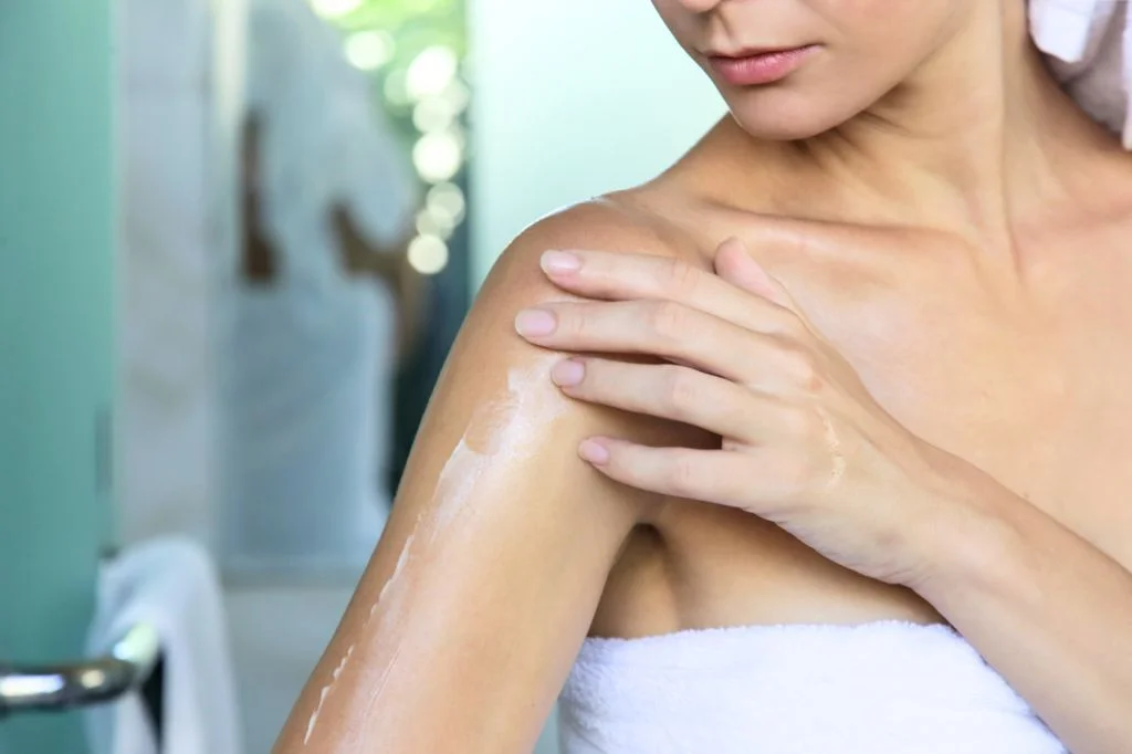 Traveler applying moisturizer to their arm in a hotel room in Bali