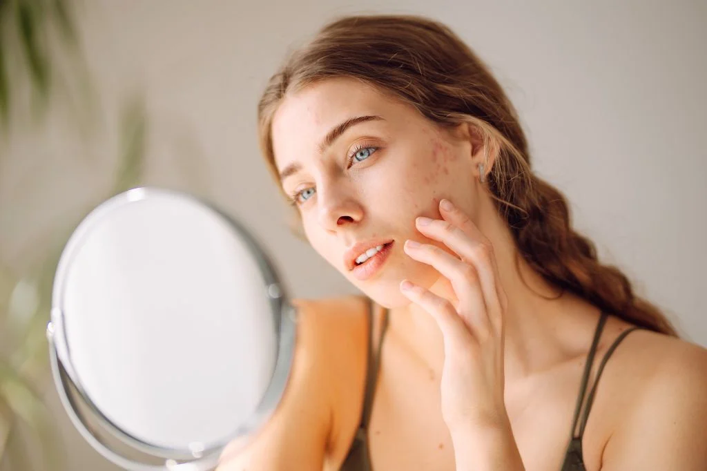 Person looking thoughtfully at their reflection, considering their skin