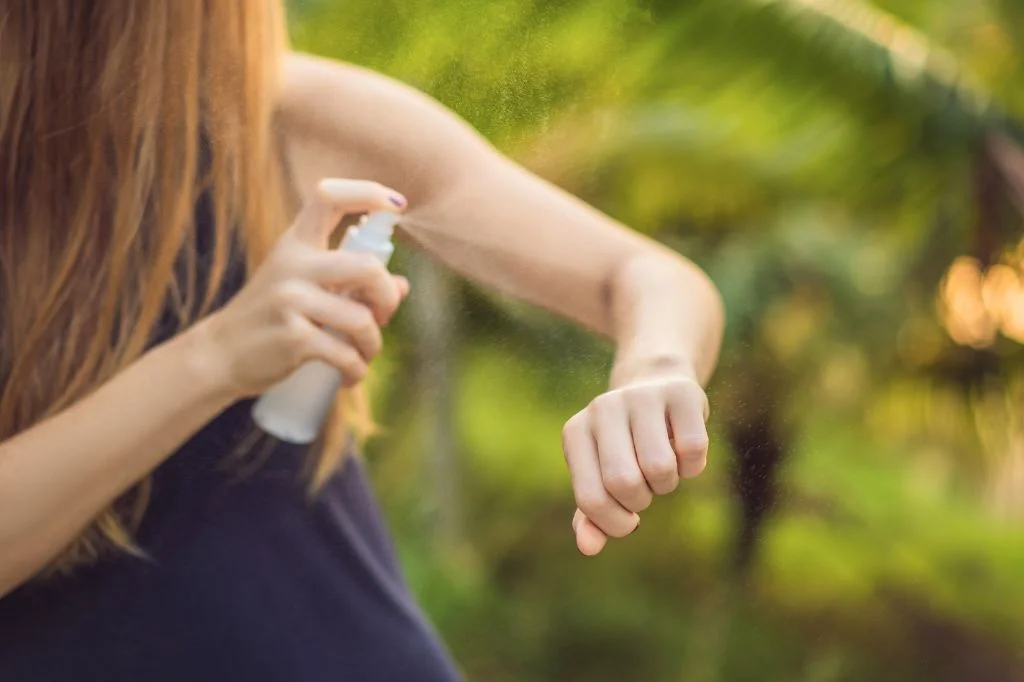 Traveler applying insect repellent outdoors in Bali in the evening