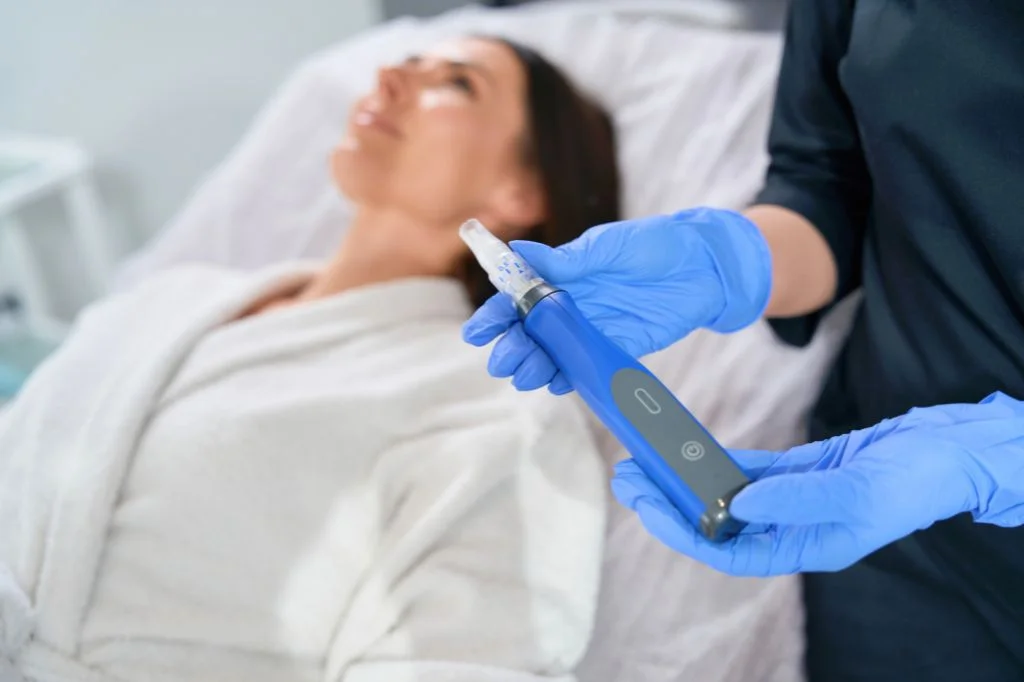 Dermatologist holding a microneedling pen device in a bright, modern clinic room