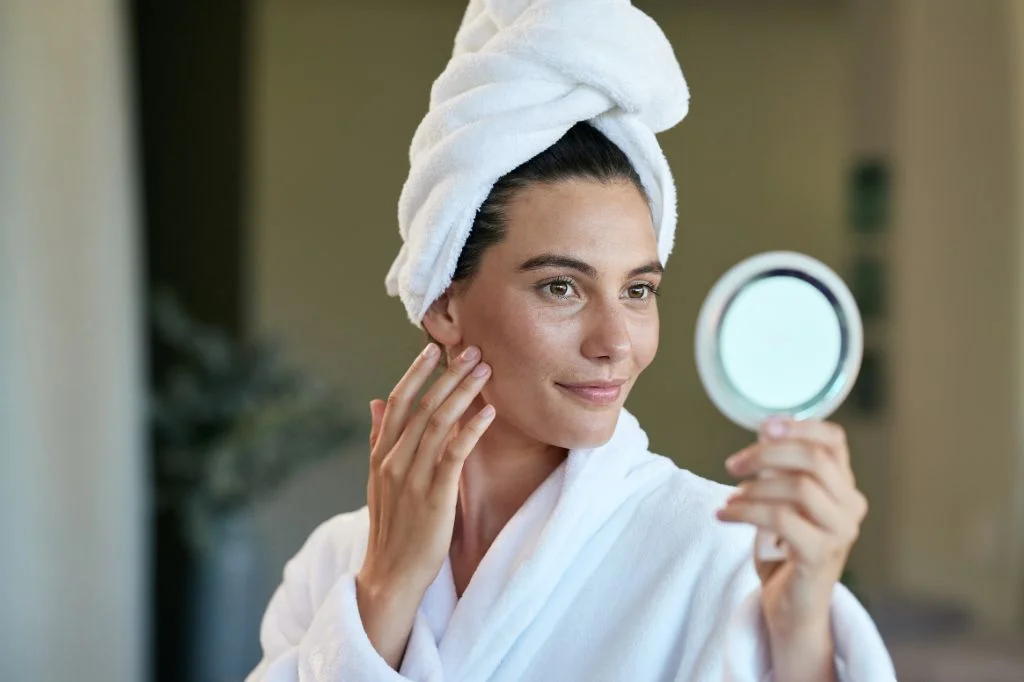 Traveler checking her reflection with a subtle, confident smile in a bright hotel bathroom mirror during a Bali holiday