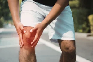 Person holding their knee in discomfort, chronic joint pain concept